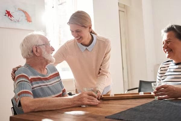 Care worker with residents at a communal table